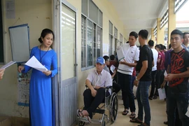Thí sinh ngồi xe lăn đến làm thủ tục thi