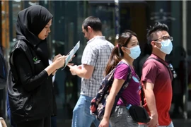 Một tình nguyện viên thuộc Bộ Truyền thông Singapore thu thập phản ánh của người dân về tình hình dịch COVID-19.