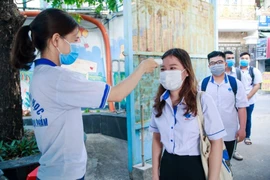 Sinh viên một trường ĐH thực hiện đo thân nhiệt khi ra vào cổng trường