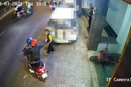 Hai thanh niên bỏ chạy sau khi tạt ca mắm tôm vào người chị T ngay trước trụ sở công ty. Ảnh chụp từ clip