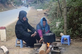Người dân sinh sống dưới chân đèo Pha Đin đốt lửa sưởi ấm, chống chọi với giá lạnh. Ảnh: TTXVN