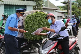 Người dân xuất trình giấy tờ cho một cán bộ tại chốt kiểm dịch. Ảnh: HOÀNG GIANG