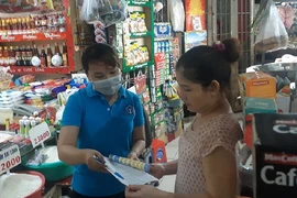Nhân viên bưu điện tư vấn các quyền lợi khi người dân tham gia bảo hiểm xã hội tự nguyện ở chợ Đa Kao, quận 1. Ảnh: N.HIỀN