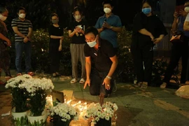Mọi người cầu nguyện cho nạn nhân tại chung cư đêm 27-12. Ảnh: NGUYỄN YÊN