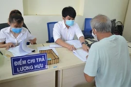 Người dân đang nhận lương hưu. Ảnh: VIẾT LONG