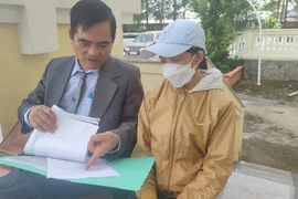 Luật sư Nguyễn Thanh Kha (bảo vệ miễn phí cho bà Dung) trao đổi với bà Dung về nội dung vụ kiện. Ảnh: NGUYỄN HIỀN