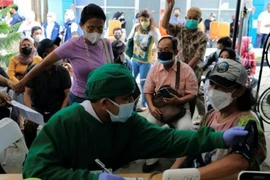 Nhân viên y tế thực hiện kiểm tra sức khỏe cho một phụ nữ trước khi tiêm mũi tăng cường ở Jakarta, Indonesia, ngày 12-1.