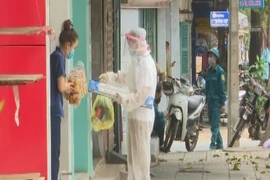 Cán bộ đi chợ giúp dân tại khu phong tỏa phòng dịch COVID-19