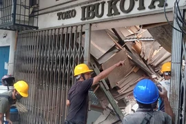 Công nhân kiểm tra một cửa hàng hư hại sau trận động đất ở khu vực Cianjur, tỉnh Tây Java (Indonesia) ngày 21-11. Ảnh: CNN