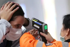 Một hành khách đến sân bay quốc tế Hong Kong đang được kiểm tra nhiệt độ. Ảnh: REUTERS