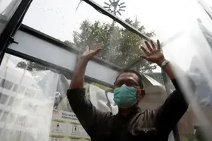 Một người đàn ông đeo khẩu trang vào buồng xịt khử trùng bên ngoài trung tâm mua sắm ở thủ đô Jakarta (Indonesia). Ảnh: REUTERS