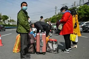 Một số người dân đang đợi xe sau khi hoàn thành thủ tục tại một chốt kiểm dịch ở Vũ Hán. Ảnh: AFP