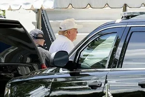 Tổng thống Trump đội mũ lưỡi trai và mặc áo phông trắng đi chơi golf. Ảnh: BLOOMBERG