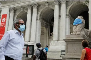 Một con sư tử đá bên ngoài Thư viện công cộng New York ở quận Manhattan của thành phố New York được mang một chiếc khẩu trang lớn. Ảnh: REUTERS