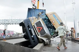 Xe container ‘vấp’ dải phân cách lật nghiêng, 13 tấn bánh ngập nước