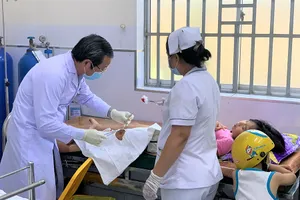 Bác sĩ Phòng khám vệ tinh Vĩnh Lộc B phối hợp với nhân viên y tế của Trạm y tế Vĩnh Lộc B xử lý vết thương cho một bệnh nhi. Ảnh: THẢO PHƯƠNG