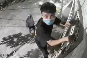 Một người trèo rào, một người cảnh giới để lấy trộm tài sản tại phường Hiệp Phú.