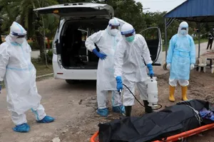 Nhân viên y tế Malaysia khử trùng thi thể bệnh nhân COVID-19 trước khi mai táng. Ảnh: THE STRAITS TIMES