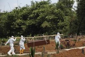 Nhân viên y tế chôn cất một bệnh nhân COVID-19 tại Indonesia. Ảnh: AFP