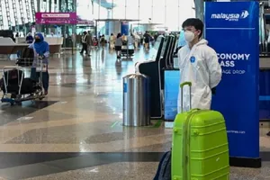 Các du khách ở sân bay quốc tế Kuala Lumpur (Malaysia) mặc đồ bảo hộ phòng dịch. Ảnh: AFP