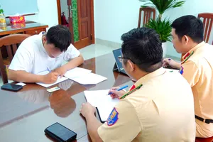 Nam thanh niên đi xe máy thả hai tay vừa xem điện thoại, vừa xỉa răng