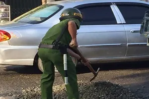Cảnh sát mua đá dăm lấp ổ gà giữa đường