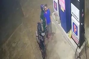Kẻ cướp kề liềm vào cổ, cướp tiền của nhân viên cây xăng. Ảnh chụp màn hình