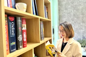 Tác giả bên kệ sách tự tay lắp ghép trong căn nhà trọ của mình. Ảnh: NVCC