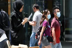 Một tình nguyên viên của Bộ Truyền thông Singapore thu thập phản hồi của người dân về tình hình dịch Corona. Ảnh: AFP