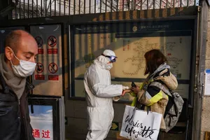 Nhân viên y tế kiểm tra sức khoẻ của một hành khách đi tàu ở ga tàu Bắc Kinh ngày 9-2. Ảnh: CNN