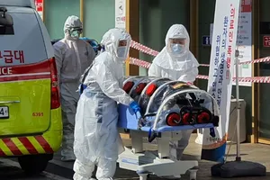 Nhân viên y tế di chuyển một người nghi nhiễm COVID-19 ở TP Daegu hôm 21-2. Ảnh: AFP
