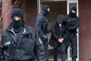 Một nghi phạm cầm đầu đường dây bị cảnh sát giải đi ngày 3-3. Ảnh: DW