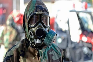 Một nhân viên y tế đeo mặt nạ trước khi khử trùng tại TP Najaf (Iraq).Ảnh: AFP