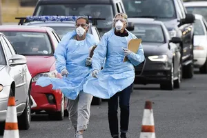 Nhân viên y tế chuẩn bị kiểm tra thân nhiệt tài xế tại một chốt kiểm soát y tế bang Colorado, Mỹ ngày 16-3. Ảnh: AFP