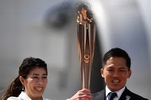 Hai VĐV Nhật Bản Tadahiro Nomura (phải) và Saori Yoshida (trái) gương cao ngọn đuốc Olympic Tokyo 2020. Ảnh: AFP.