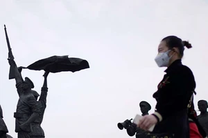 Một người phụ nữ đi ngang qua Tượng đài Cách mạng Tân Hợi ở Vũ Hán hôm 6-4. Ảnh: REUTERS