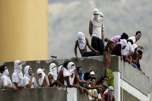 Phạm nhân tụ tập trên nóc nhà tù của cảnh sát ở thủ đô Caracas (Venezuela) trong một vụ bạo loạn năm 2015. Ảnh: REUTERS