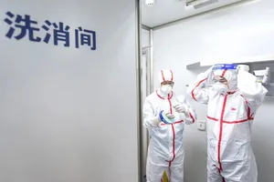 Hai nhà nghiên cứu thực hiện quy trình an toàn trước khi vào làm việc trong phòng thí nghiệm của Viện Virus học Vũ Hán, tỉnh Hồ Bắc, Trung Quốc. Ảnh: TÂN HOA XÃ