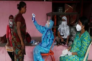  Nhân viên y tế kiểm tra nhiệt độ người dân trong chiến dịch kiểm tra COVID-19 tại Mumbai (Ấn Độ) ngày 13-7. Ảnh: REUTERS