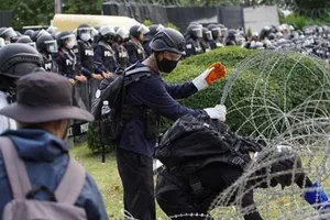 Người biểu tình cố gắng di chuyển hàng rào kẽm gai trước cổng Trung đoàn bộ binh 11. Ảnh: REUTERS