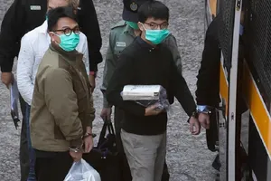 Hoàng Chi Phong (áo đen, quần xám) và Lâm Lãng Ngạn (áo nâu, quần đen) được áp giải đến tòa ngày 2-12. Ảnh: AP