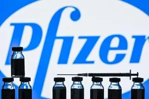 Những lọ vaccine ngừa COVID-19 xếp trước logo tập đoàn dược phẩm Mỹ Pfizer.