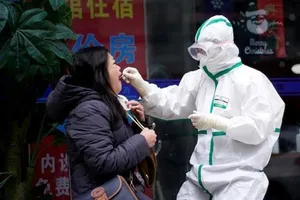 Một nhân viên y tế Trung Quốc đang lấy mẫu xét nghiệm từ một phụ nữ.