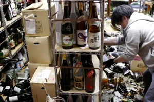 Một công nhân dọn dẹp chai vỡ tại một cửa hàng bán rượu sau trận động đất ngày 13-2. Ảnh: KYODO/REUTERS
