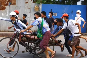 Người biểu tình Myanmar hỗ trợ một người biểu tình khác bị thương ở TP Mandalay ngày 13-3. Ảnh: AP