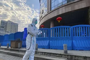 Một nhân viên mặc đồ bảo hộ và mang thiết bị khử trùng bên ngoài Bệnh viện Trung ương Vũ Hán. Ảnh: AP