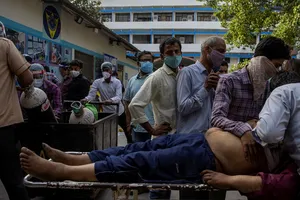 Một người đàn ông chết do COVID-19 khi chờ nhập viện hôm 23-4, trong khi các nhân viên y tế chuyển các bình oxy tới khu vực điều trị bệnh nhân COVID-19. Ảnh: REUTERS