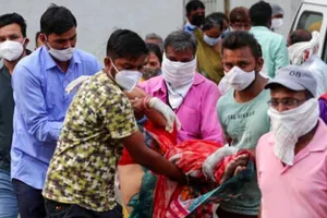 Người thân khiêng người vợ ngất xỉu sau khi nhìn thấy thi thể chồng chết vì COVID-19, ngày 27-4.