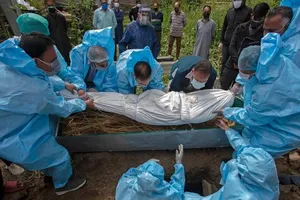 Các nhân viên y tế Ấn Độ mặc đồ bảo hộ đưa thi thể một bệnh nhân COVID-19 vào quan tài. Ảnh: AFP