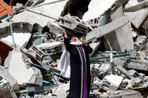 Một phụ nữ đứng khóc gần đống đổ nát của một tòa nhà đã bị phá hủy trong một cuộc không kích của Israel ở Dải Gaza, ngày 16-5.